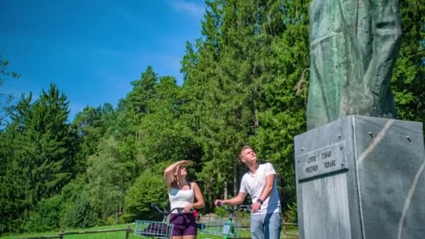 Unga Par Med Cyklar Står Bredvid Minnesstaty Lovro Kuhar Prezihov — Stockvideo