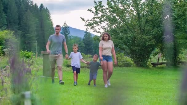 Família Jovem Andando Longo Grama Park River Segurando Mãos Acenando — Vídeo de Stock