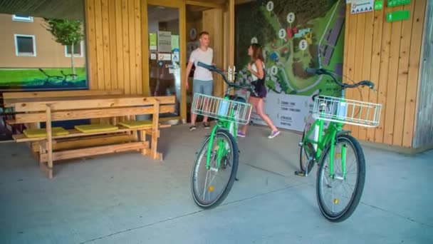 2人の若い旅行者が宿泊施設から出てレンタル自転車を手に入れます ドリーアウト — ストック動画