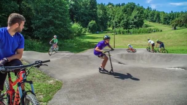 Παιδιά Κάνουν Ποδήλατο Στην Πίστα Έναν Ενήλικα Προσέχει Την Ασφάλειά — Αρχείο Βίντεο