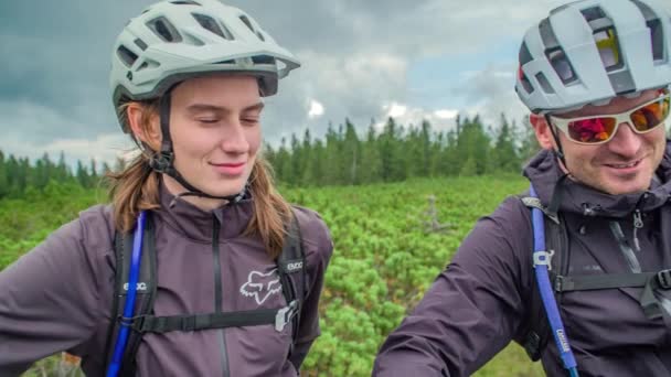 Два Велосипедиста Шлемах Смотрят Улыбаются Красивая Зеленая Природа Вокруг — стоковое видео