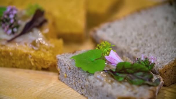 Zbliżenie Kawałek Chleba Domowej Roboty Ozdobiony Jadalnymi Kwiatami Ziołami Zielenią — Wideo stockowe