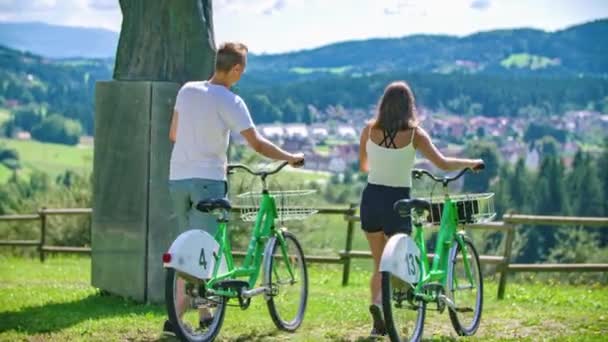 Junges Paar Spaziert Mit Leihrädern Durch Park Und Bleibt Denkmal — Stockvideo