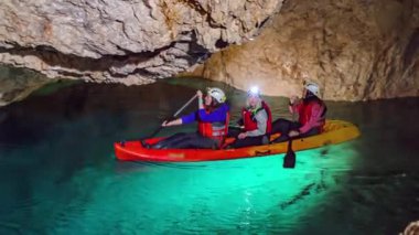 Mezica 'nın Glancnik kentindeki eski tarihi madendeki yeraltı kanosunun tadını çıkaran turistler. Düşük açı, ön görünüm.