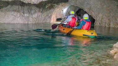 Slovenya 'nın Peca dağının yeraltı sularında kano süren ziyaretçilerin arka manzarası