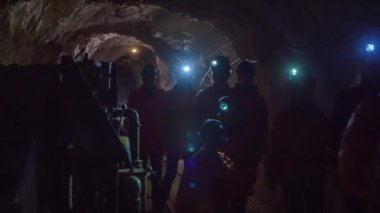 Turistler yeraltındaki karanlık tünelden geçerek eski altın madenlerini geziyorlar.