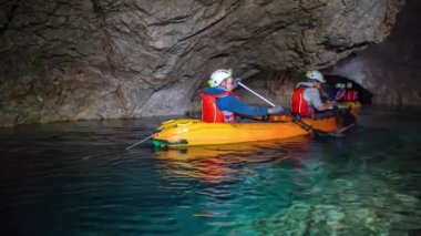 Mezica 'nın Glancnik kentindeki eski tarihi madendeki yeraltı kanosunun tadını çıkaran turistler. Düşük açı, ön görünüm.