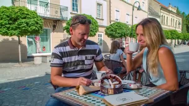 屋外のトレンディーなカフェでコーヒーを飲んでいる幸せな笑顔のカップル スロベニアのGradec — ストック動画