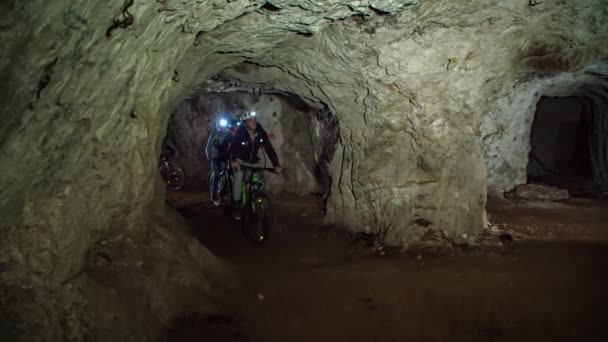 骑专业山地自行车的骑自行车者在地下游览时穿过一个岩石矿山的狭窄隧道 梅兹卡 斯洛文尼亚 — 图库视频影像