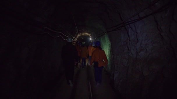 観光客の家族は古い神の鉱山の教育ツアーで地下トンネルを歩く — ストック動画