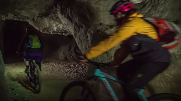 Δύο Αθλητικοί Ποδηλάτες Επαγγελματικά Ποδήλατα Διασχίζουν Ένα Σκοτεινό Ορυχείο Βραχώδη — Αρχείο Βίντεο