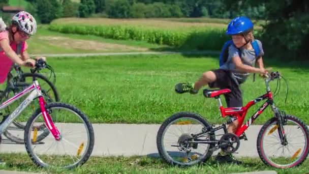 2人の陽気な子供たちは 両親とサイクリングした後 遊び場で楽しんでいます — ストック動画