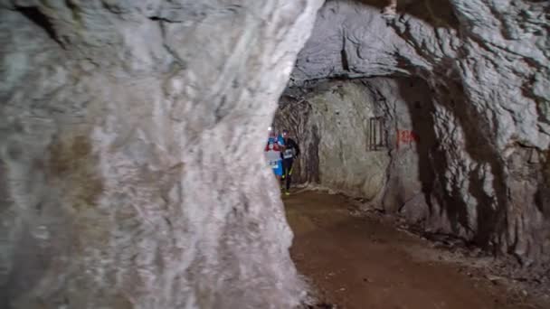 跑步者穿着适当的跑步服装 用前灯火把穿过黑暗的洞穴 前景全景 — 图库视频影像