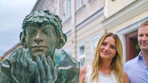 Unge Par Nærmer Sig Springvand Statue Med Lukkede Øjne Undersøger – Stock-video