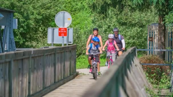 父母和孩子 骑自行车 带着保护装置在旧木桥上 — 图库视频影像