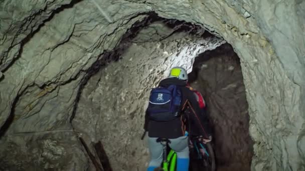 跟着两个骑山地自行车的人在洞穴探险的镜头 从后面 — 图库视频影像