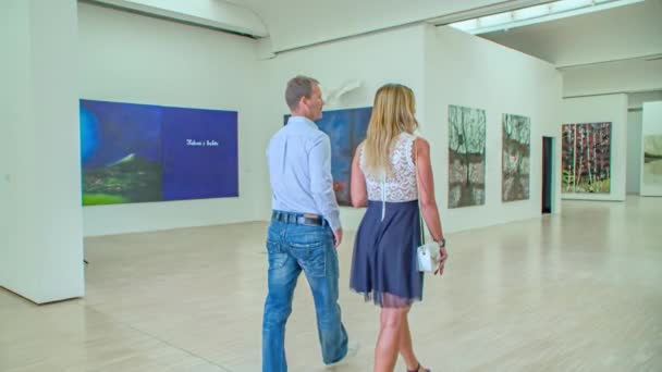 Young Couple Walks Art Gallery Admires Paintings Tracking Shot — Stock Video