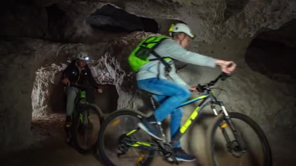 山地采矿隧道下骑自行车路线的潘射击 看到一群骑自行车的人穿过狭窄的通道 — 图库视频影像