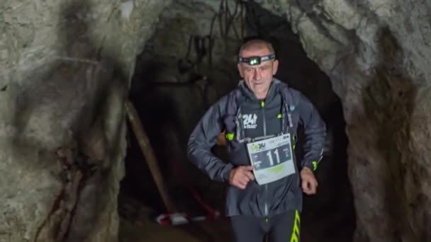 前から2人の男が走っている姿を映し出し ヘッドライトトーチで暗い自然洞窟を通って — ストック動画