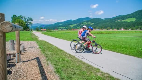 背景に山のある田舎道を自転車に乗っている兄弟のスローモーション — ストック動画