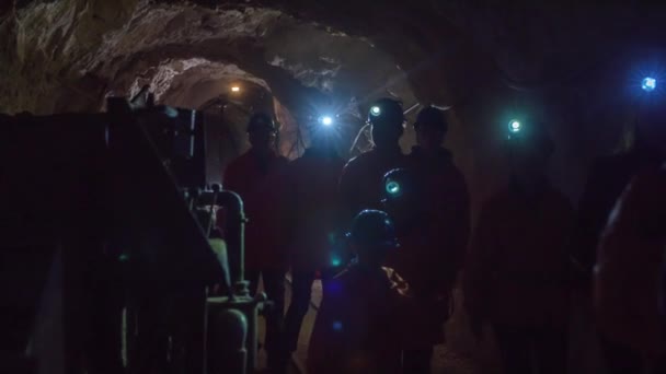 観光客は古い金鉱山の教育ツアーで地下の暗いトンネルを歩く — ストック動画