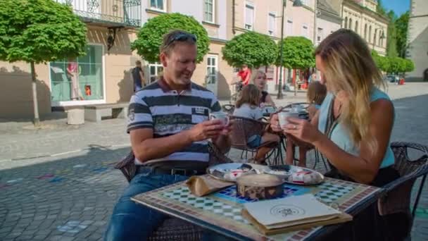 カフェの外に座っている間にコーヒーを飲んでいるカップルの軌道ショット — ストック動画