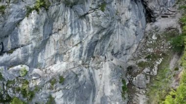 Geriye doğru hareket eden hava aracı görüntüleri bir dağcının dik ve kayalık dağlık arazide ilerlediğini gösteriyor. Macera anlayışı ve ekstrem spor anlayışı..