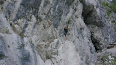 Geriye doğru hareket eden insansız hava aracı görüntüleri, bir dağcının, dik ve kayalık dağlık arazide amacına ulaştıktan sonra heyecanlandığını gösteriyor..