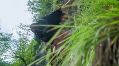 Dik bir dağ duvarına tırmanan bir adamın düşük açılı çekimi. İp ya da güvenlik ekipmanı olmadan. Sadece çıplak ellerinin kuvvetiyle..