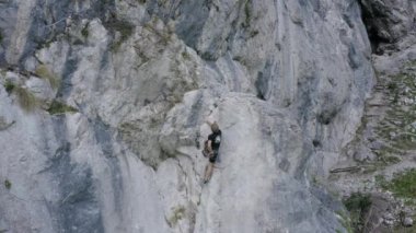 Hava aracı görüntüleri bir dağcının dik ve kayalık dağlık araziyi geçtiğini gösteriyor. Macera ve ekstrem spor anlayışı.