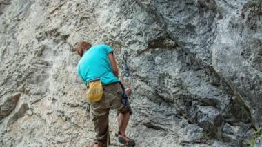 Genç maceraperest dağcı, dik ve kayalık dağa tırmanıyor. Macera ve ekstrem spor anlayışı. Aşağıdan görüntüle.