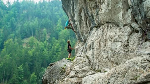 Twee Mannen Klimmen Een Hoge Steile Muur Bergen Met Sparrenbos — Stockvideo