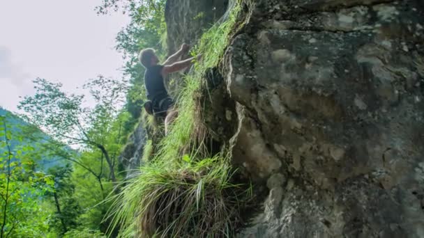 若い冒険的な男は 任意のロープなしで急な岩の上に屋外で岩をボルダリング 冒険と極端なスポーツの概念 下からの眺め — ストック動画