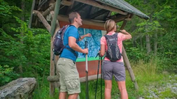 男と女が地図を見てる 興味のある場所を指しています ハイキングアドベンチャー Topla Valley スロベニア — ストック動画