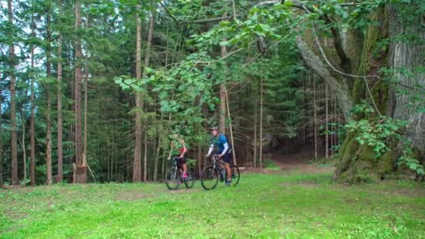 Couple Ride Bikes Grassy Pathway Green Lush Forest Slow Motion — Stock Video