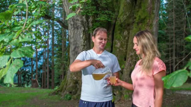 Attraktives Ehepaar Trinkt Eistee Unter Großem Baum Outdoor Park — Stockvideo
