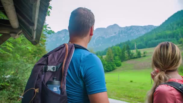トレッキング旅行の人々のバックビューでは 山の風景や水平線の緑の谷を指しています ショット中肩越しに — ストック動画