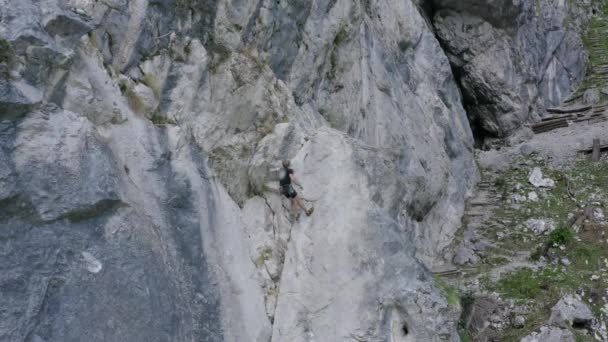 向前移动的无人驾驶飞机镜头 显示一名登山者穿过陡峭的岩石山脉地形 冒险和极限运动的概念 — 图库视频影像
