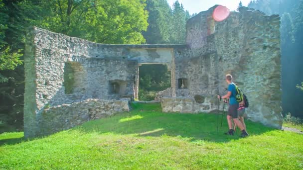 スロベニアのヴゼニツァで古代遺跡を探索する観光客のハイカーカップル — ストック動画