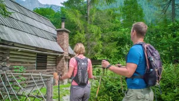 Ein Neugieriges Paar Wanderer Mit Stöcken Erreicht Eine Holzhütte Inmitten — Stockvideo
