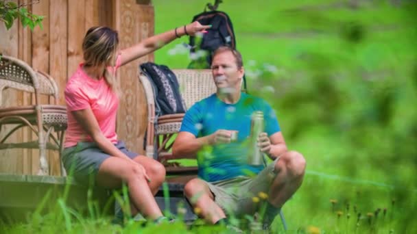 在森林里的一座木头房子附近 一对游手好闲的夫妇正在休息和喝酒 — 图库视频影像