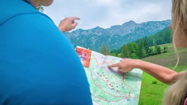 从一个男人和一个女人的肩膀上看到一张地图 寻找通向高山的方向 — 图库视频影像