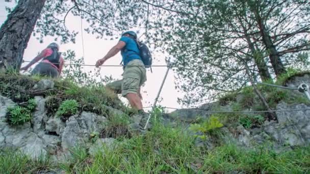 两个徒步旅行者到达陡峭的山路顶上 举起手来庆祝 低角度 — 图库视频影像