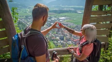 Çiftler elleriyle kalp yapar. Arka planda çok güzel bir manzara var. Yeşil pencere, Slovenya