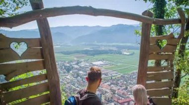 Yaylım ateşi düştü. Bir köye ve dağlık araziye bakan bir çift. Yeşil pencere, Slovenya