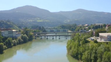 Nehirdeki köprü, geçen arabalar ve nehrin her iki yakasında bir şehir.