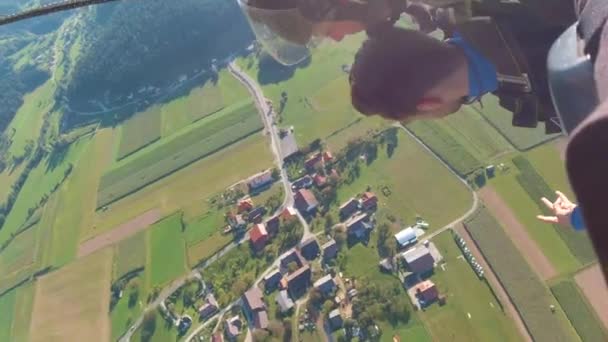 Съемка Воздуха Двух Мужчин Прыгающих Парашютом Красивым Ландшафтом Зелеными Полями — стоковое видео