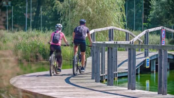 Jovem Casal Andar Bicicleta Caminho Madeira Ponte Sobre Água Verde — Vídeo de Stock