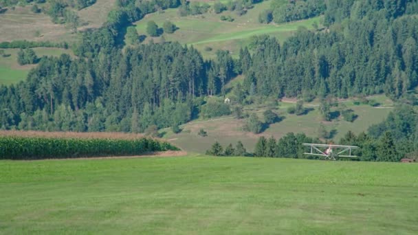 在丘陵地带的绿地上 螺旋桨式的小运动型飞机在远处起飞 — 图库视频影像