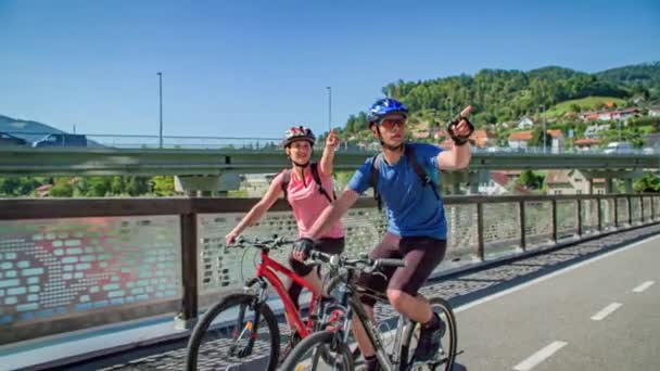 Två Cyklister Trampar Bron Över Slovenj Gradec Slovenien Långsamma Rörelser — Stockvideo